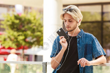 男子时装技术城市风格服装概念穿着牛仔服站在市街上穿着牛仔服的男子穿短裤牛仔着长着便衣服短在电话中讲图片