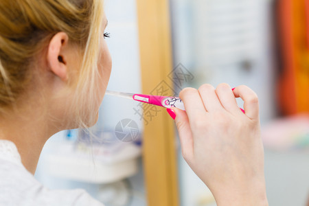 洗刷牙齿的女子洗刷牙金发女孩洗手间有牙刷的金发女孩看着镜子口腔卫生洗刷牙的女子在洗手间刷牙背景图片