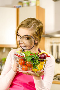 妇女使用放大玻璃槽许多彩蔬菜调查购物篮健康的饮食生活方式营养素食品寻找杀虫剂和化学品图片