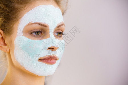 年轻女孩脸上戴白绿色的泥面罩少女照顾油皮肤清洗毛孔美容治疗皮肤护理白绿色的泥面罩女孩脸上戴白绿色的泥面罩背景图片