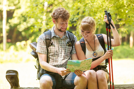 男人和女游客随身携带行李在休息时阅读森林之旅几位远足者在寻找方向指南背包暑假冒险图片