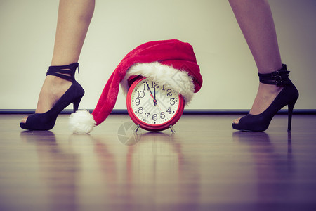 穿着高跟鞋和闹钟的女子穿着圣达克萨斯帽子圣诞时节概念穿着高跟鞋的女子带着闹钟的女子圣诞节图片
