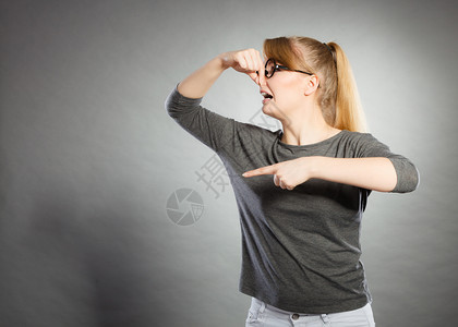 脏兮的卫生垃圾概念神经质女孩拿着鼻子戴眼镜的金发女孩拿着眼镜抓气味恶心的图片