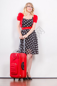 旅行度假概念身穿Polka点黑礼服准备旅行的红色手提箱身穿全着Polka点黑礼服的优雅年轻女子图片