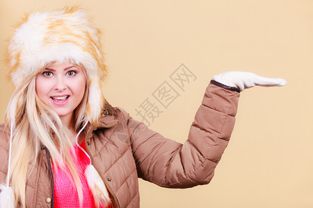 时装概念穿着俄罗斯风格和夹克的金发女郎穿着雪衣和服指着手套里的东西图片