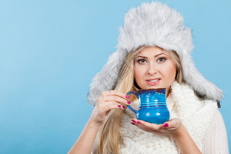 穿着红色越野衣和冬季毛的女温暖帽子拿着喝杯里的热饮图片