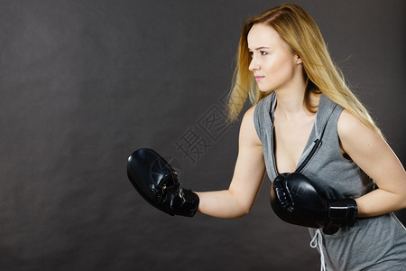 运动技巧竞和健壮的身体年轻女打拳击金发女孩戴黑色拳击手套运动和健身权力锻炼对灰色的侧视拳击女孩用手套练习图片