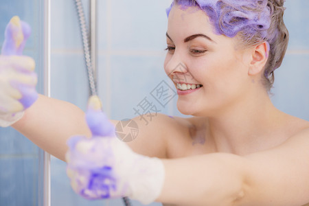 在金发上涂紫色墨粉洗发水时戴乳胶保护手套的妇女高清图片