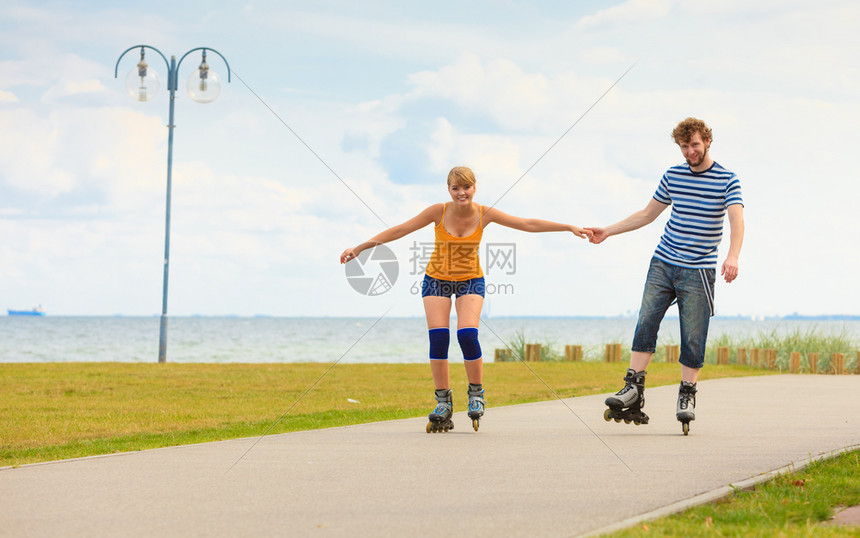 度假活跃的人和友谊概念穿滑溜冰雪的年轻情侣在海边户外游玩男女在赛道上一起滚车图片