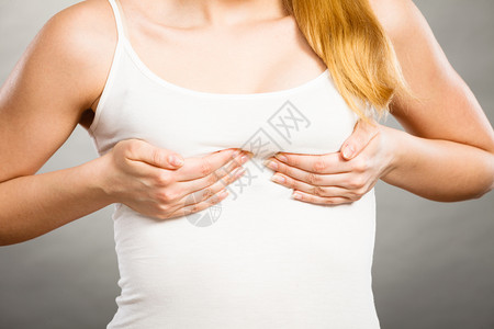身着t恤的年轻女将手握在乳房上并将她们推向胸前背景