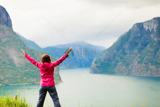 旅行概念自由游妇女快乐享受手举起来望着挪威的fjords山在挪威的Norwegian山码头举起手来的妇女图片