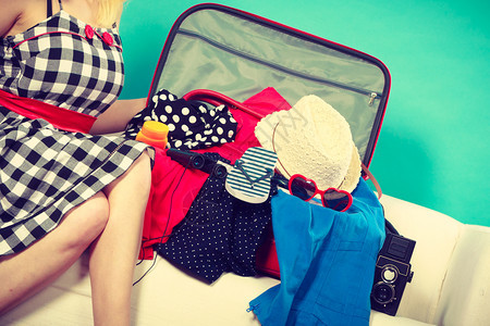 女人坐在沙发上准备度假选择衣服包装在手提箱里女人选择东西包装在手提箱里图片