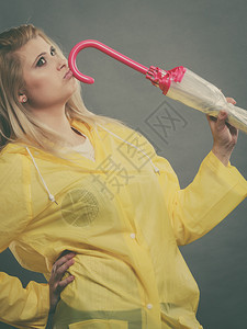 以为穿着黄色雨衣的金发女人拿着闭雨伞图片
