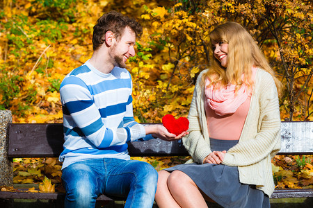 接受和分享感情用浪漫的姿态表达爱和意积极反应坐在公园里的男人坐在长椅上给快乐的女孩送上心玩具男人在秋天公园里对女孩表示感情图片