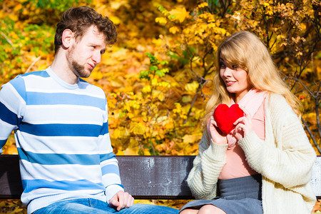 接受和分享感情用浪漫的姿态表达爱和意积极反应坐在公园长椅上的对等妇女向男人展示心玩具女孩在秋天公园向男人展示感情图片