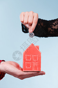 未来计划的储蓄人们手握着红色的小猪银行和币钱是家庭更好的生活人们手握着小房子和银币图片