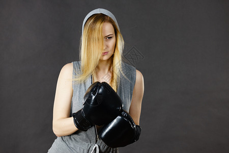 戴头罩的年轻女子打拳击金发美女戴黑色拳击手套运动和健身权力锻炼穿