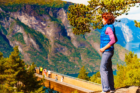 Stegastein的旅游女客在望着挪威的fjord山景Hikking旅途放松全国游景点路线Aurlandfjellet旅游者享图片