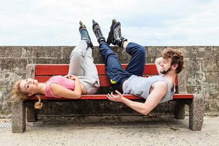 青年朋友穿着滑冰鞋训练服男女在户外休息长凳上放松青年朋友在长凳上放松图片