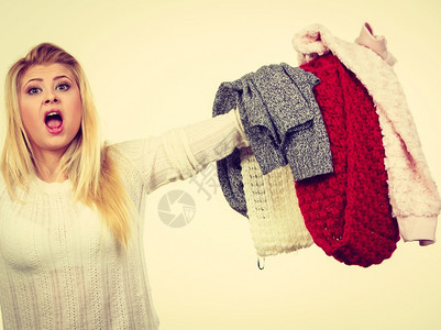 时装服两难概念年轻金发女青年孩拿着一大堆温暖的冬衣不能决定穿什么装饰形象图片