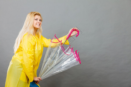 穿着黄色雨衣的金发女子拿着透明的雨伞玩得开心穿着雨衣的女子图片