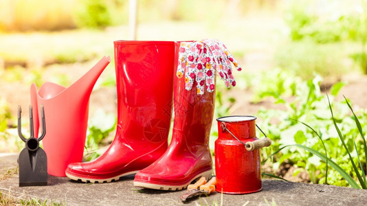 花园露户红色橡胶靴子和水罐图片