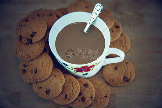 黑巧克力饼干和咖啡杯在木制桌边的黑巧克力饼干和咖啡的景象其背是孤立的图片