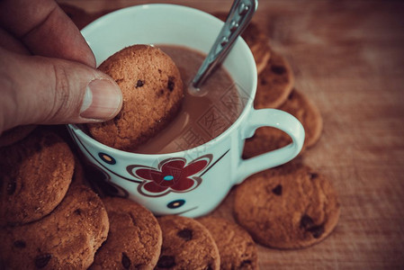 黑巧克力饼干和咖啡杯在木制桌边的黑巧克力饼干和咖啡的景象其背是孤立的图片