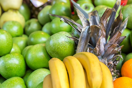 许多新鲜香蕉苹果和菠萝在杂货食品商店的摊位上销售许多新鲜香蕉苹果和菠萝都在销售背景