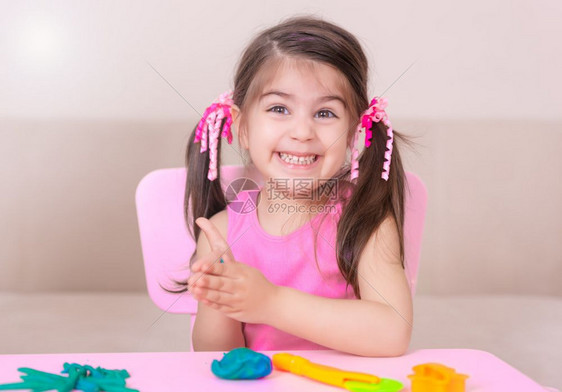 母亲和可爱的女孩坐在桌子上玩橡皮泥图片