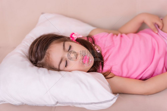 可爱女孩的肖像睡在一张床上嘴里有奶选择焦点和很小田地可爱女孩的肖像睡在一张床上有奶嘴图片