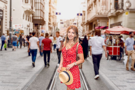 穿着红裙子的漂亮女人站在土耳其伊斯坦布尔Beyoglu区的Istiklal街上图片