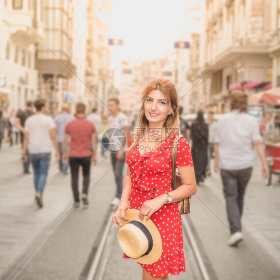 穿着红裙子的漂亮女人站在土耳其伊斯坦布尔Beyoglu区的Istiklal街上图片