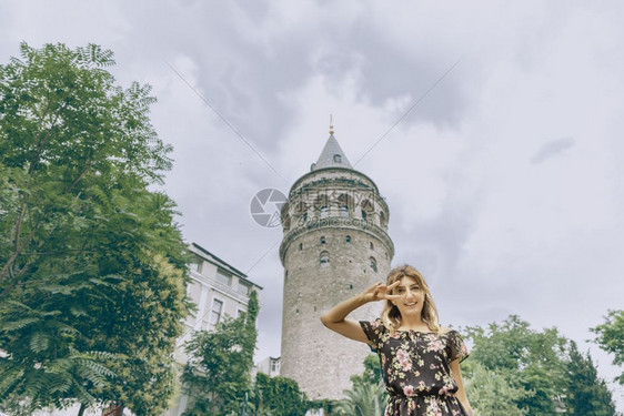 身着黑色裙子的漂亮女人站在土耳其伊斯坦布尔Beyoglu的标志加拉塔前身着黑色裙子的漂亮女人站在标志加拉塔前图片