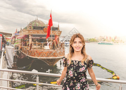身着裙子的美女站在船前土耳其伊斯坦布尔出售烧烤鱼图片