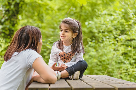 年轻妈和她的小女孩一起在森林中的木板凳上玩得很开心图片