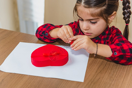 可爱的小女孩在白纸上画出红色的心形图片