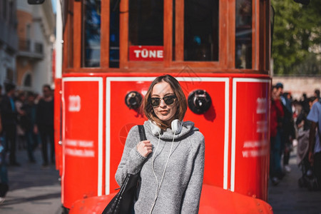 身着时装服的漂亮女孩在土耳其伊斯坦布尔流行的Istiklal街的电车前站立图片
