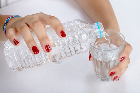 一名年轻妇女用塑料瓶装水倒了一杯图片