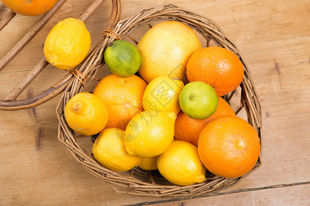 橙子柠檬和葡萄油放在木制桌上的一小篮子里图片