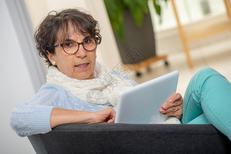 在家用数码平板电脑戴眼镜的迷人黑发高贵女背景图片