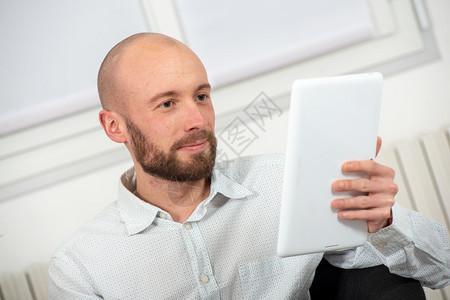 带着胡子笑的年轻人使用数字平板电脑图片