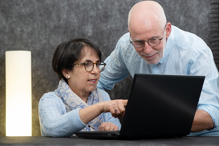 老年情侣在家使用笔记本电脑背景图片