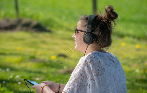 一名年轻少女在公园用耳机听音乐图片