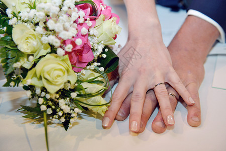 手和戒指放在婚礼花束上图片
