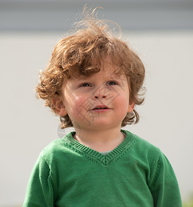 一个年轻男孩的肖像绿色毛衣在户外玩图片