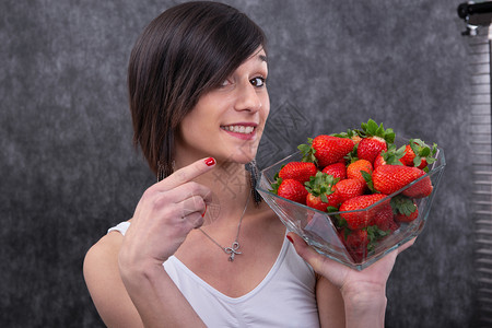 一个漂亮的年轻黑发女人吃草莓图片