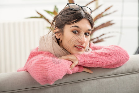 一个年轻黑发女人穿着粉红色毛衣睡在沙发上图片