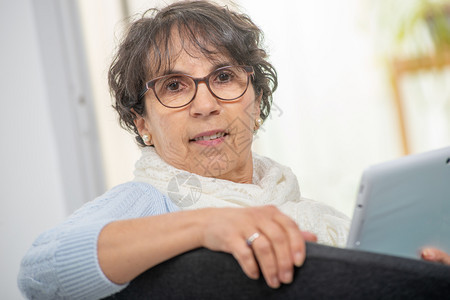 一位迷人的黑发美女戴着眼镜在家里用数字平板电脑戴眼镜背景图片