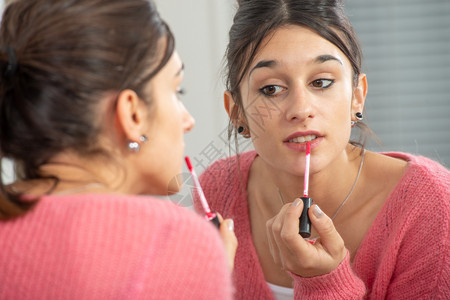 一个年轻的黑发女人在镜子里化妆图片